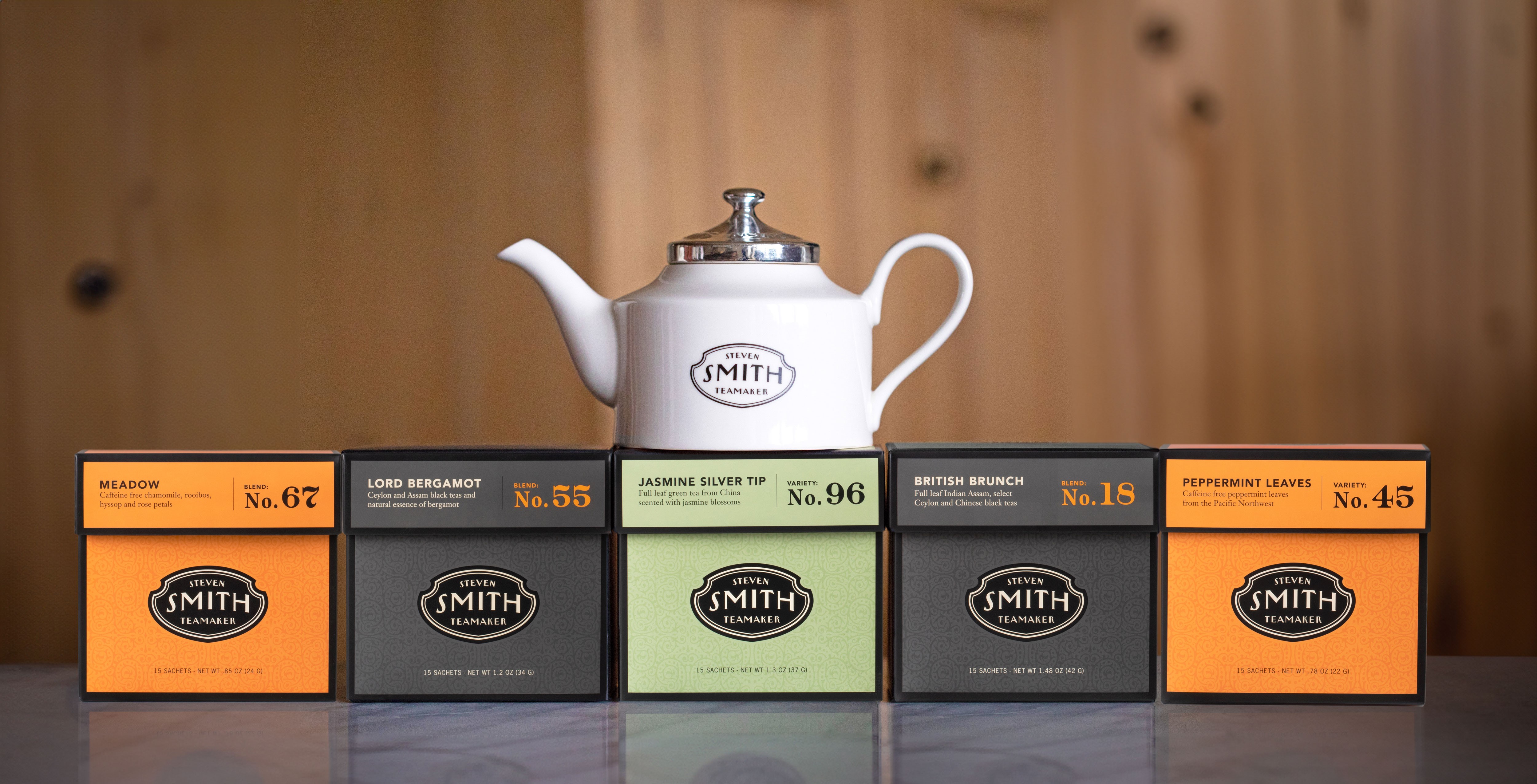 Five boxes of tea with a tea pot sitting on top of the center box.