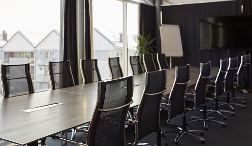 photo of an empty boardroom with a long wood table and several black chairs
