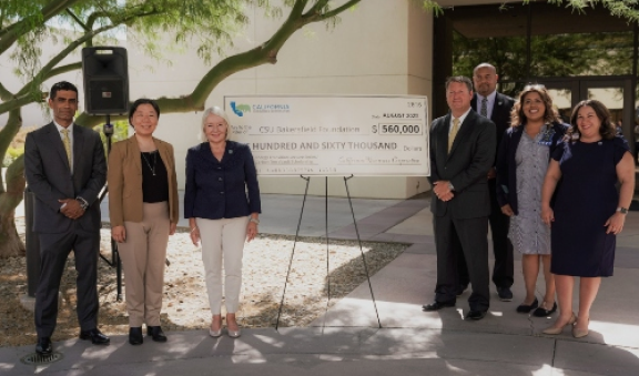 People standing in front of California State University of Bakersfield with a large check