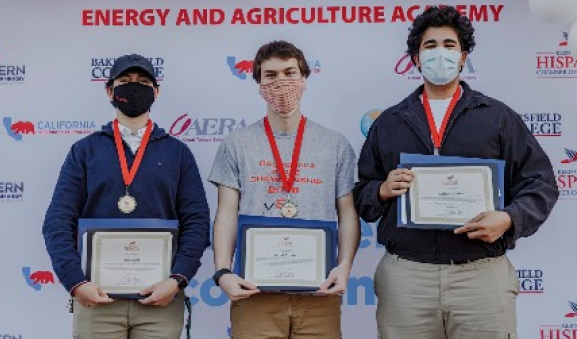Three young men standing holding certificates