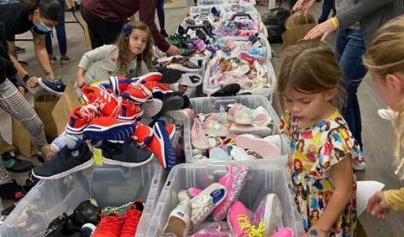 Children near crates of shoes during a shoe drive