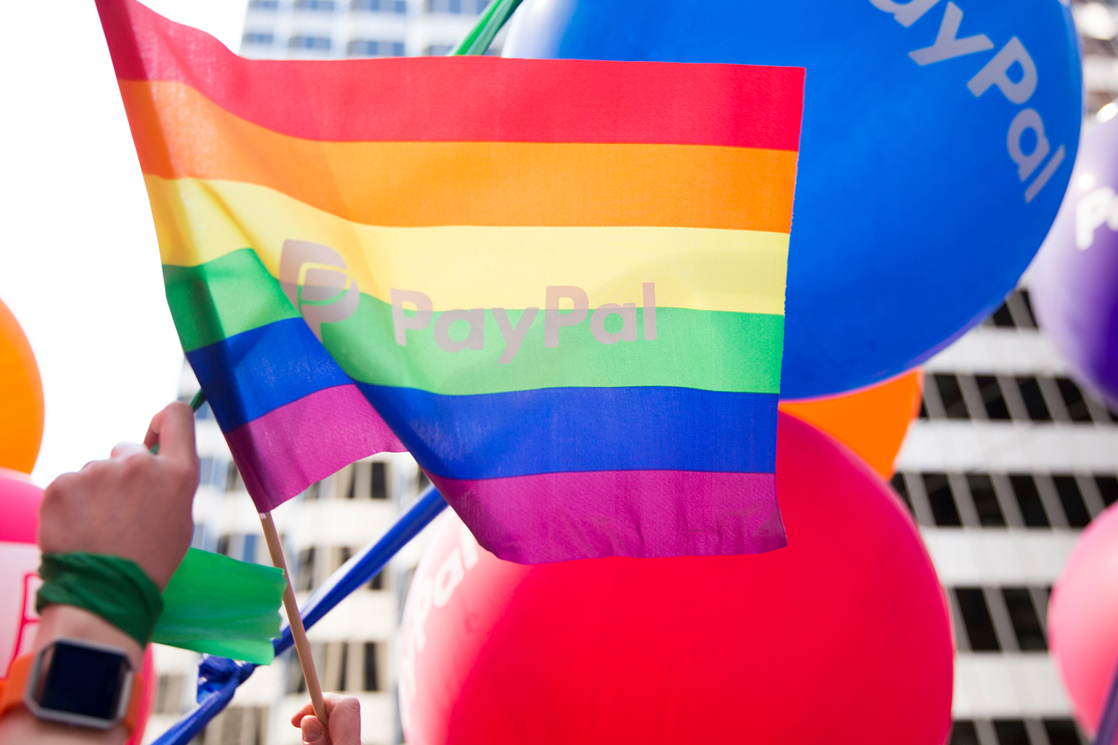 person holding pride flag with paypal logo.