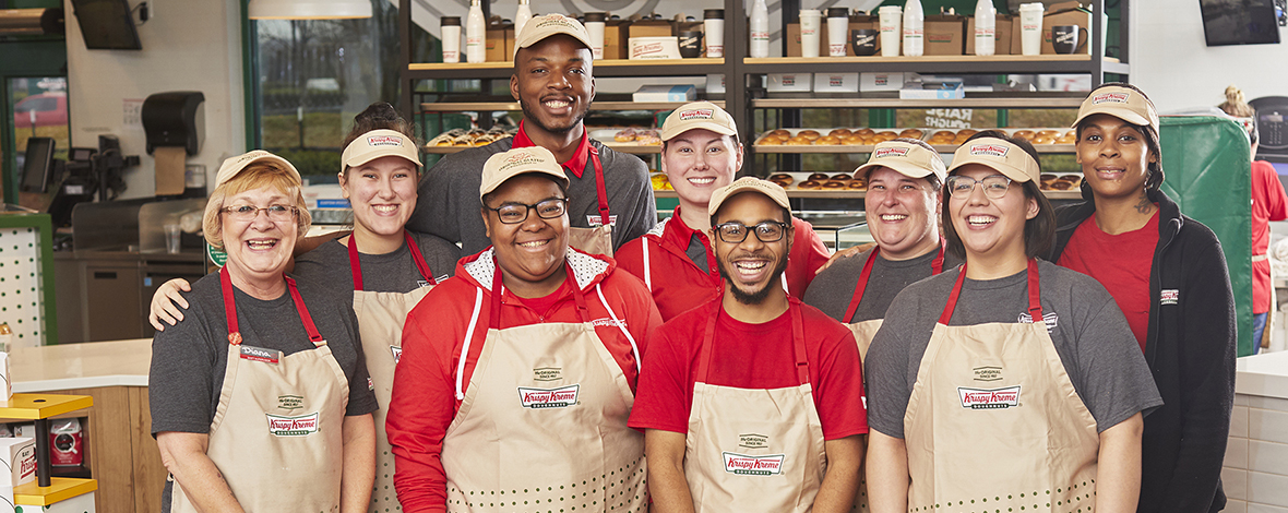 Smiling Krispy Kreme team members in a donut shop
