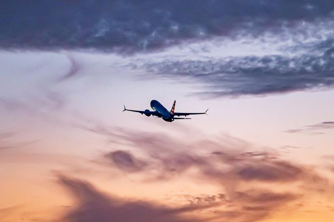 An American Airlines 737 Max flying towards a beautiful sunset
