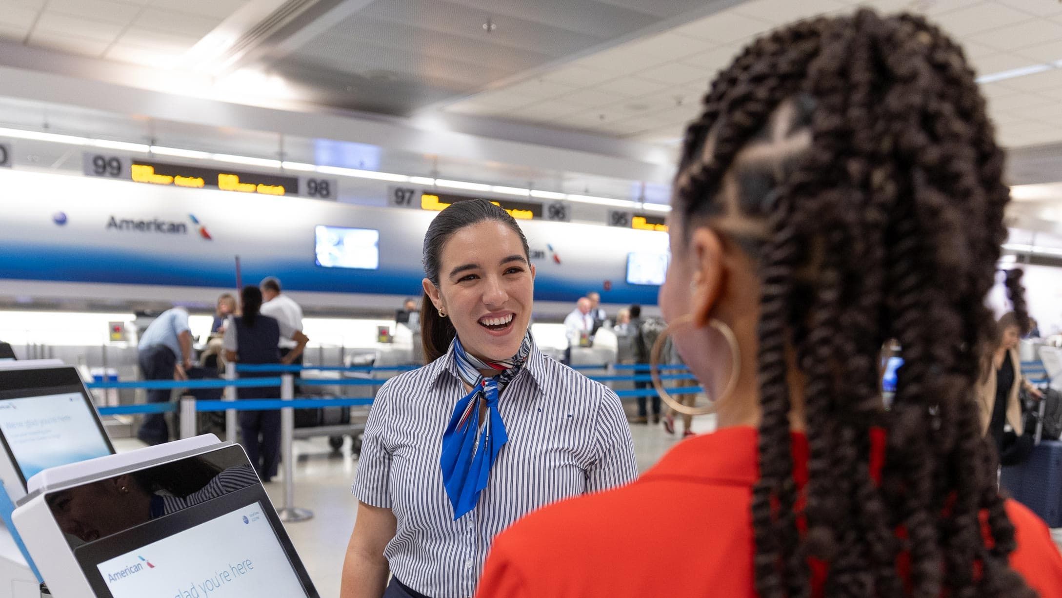 An American Airlines desk agent assists a customer with a digital kiosk