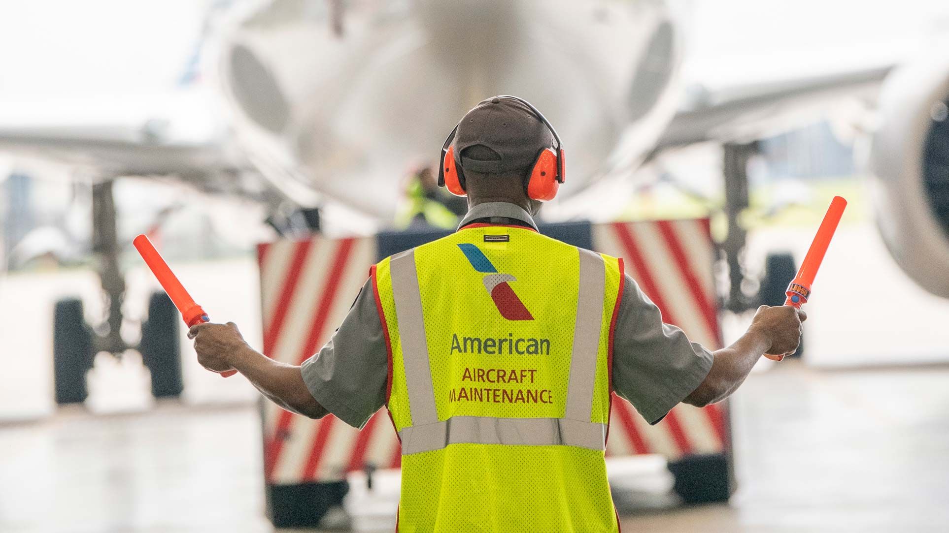 A maintenance worker guiding a plane into a hangar